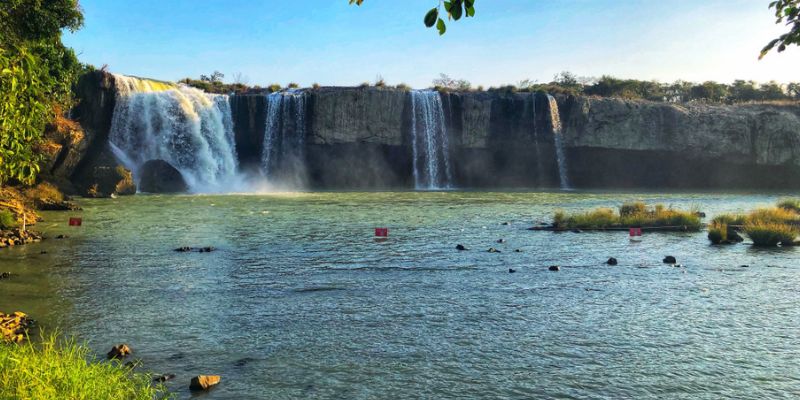 Thác Dray Nur là một trong những địa điểm thuộc khu vực tỉnh Tây Nguyên và nổi tiếng với danh xưng “thủ phủ cà phê”. Nơi đây có rất nhiều cảnh đẹp thơ mộng gắn liền với cảnh sắc thiên nhiên hùng vĩ. Do vậy, bạn sẽ có được những trải nghiệm đáng nhớ khi ghé thăm địa điểm này cùng gia đình. Tổng quan về thác Dray Nur Ngay tại khu vực Đắk Lắk , bạn có thể ghé đến hệ thống thác nước nổi tiếng là Dray Sap - Dray Nur - Gia Long. Tuy nhiên, thác Dray Nur lại là một trong 2 nhánh thác được phân chia bởi sông Sê-rê-Pôk và Dray Sap. Do vậy, thác nước này còn có tên gọi đặc biệt khác là “thác vợ” với hình ảnh dịu dàng, nhẹ nhàng như người vợ thảo. Đây là hình ảnh dòng thác với vẻ đẹp dịu dàng khiến nhiều người thích thú khi ghé thăm. Nơi đây gắn liền với nhiều câu chuyện truyền thuyết thú vị giúp bạn được chiêm ngưỡng trọn vẹn cảnh sắc hùng vĩ. Đặc biệt, du khách còn được thưởng thức các ẩm thực đặc trưng mang đậm dấu ấn Tây Nguyên. Dòng thác này nằm ngay dòng sông Sê-rê-Pôk thuộc giáp ranh của 2 tỉnh Đắk Lắk và Đắk Nông nên rất dễ di chuyển. Đây là địa điểm nằm dọc trên quốc lộ 14 nên khi tìm kiếm đường ghé đến khá đơn giản và nhanh chóng. Toàn cảnh ngọn thác Dray Nur Hướng dẫn di chuyển thác Dray Nur chi tiết và cụ thể Thác nước nằm cách xa trung tâm thành phố Buôn Mê Thuột khoảng 20km. Đây là dòng thác nằm dọc trên Quốc lộ 14. Do vậy, việc tìm kiếm cũng không quá khó khăn nếu du khách lựa chọn phương tiện di chuyển phù hợp. Đầu tiên, trước khi ghé đến dòng thác, bạn phải di chuyển đến tỉnh Đắk Lắk. Du khách có thể chọn di chuyển bằng xe máy, xe khách hoặc máy bay tùy nhu cầu. Đây là địa điểm có sẵn sân bay nên việc bay thẳng vào thành phố cũng tiết kiệm rất nhiều thời gian. Sau đó, bạn có thể di chuyển đến khu vực thác Dray Nur thông qua xe buýt hoặc phương tiện xe máy/ô tô. Nếu du khách chọn di chuyển bằng xe buýt, bạn có thể chọn tuyến đi số 13 xuất phát từ ngã 6 xe tăng và dừng tại cổng thác. Di chuyển đến dòng thác Dray Nur đơn giản Thời điểm hoàn hảo để tham quan thác Dray Nur Đắk Lắk là khu vực nằm trên vùng đất Tây Nguyên nên thời tiết quanh năm khá mát mẻ và dễ chịu. Đặc biệt, từ tháng 11 trở về cuối năm, Đắk Lắk sẽ rơi vào mùa khô với trời nắng đẹp và se lạnh về đêm. Do vậy, không khí tại nơi đây rất phù hợp để bạn ghé thăm và vui chơi. Thời điểm này du khách có thể chiêm ngưỡng các cảnh đẹp trù phú và huyền bí của dòng thác. Tuy nhiên, nếu bạn muốn bơi lội và vui chơi cùng gia đình, du khách có thể chọn tháng 2 hoặc tháng 4 vì nước sẽ ấm hơn và có nhiều cảnh đẹp với ánh nắng chan hòa. Tham quan thác Dray Nur vào tháng 11 trở về cuối năm Trải nghiệm tại thác Dray Nur có những gì đặc biệt? Với những vị khách mới tham quan dòng thác tuyệt đẹp này lần đầu tiên, ngoài việc choáng ngợp trước cảnh sắc thiên nhiên xung quanh khu vực này, bạn có thể tham quan các địa điểm quanh thác dưới đây để có một ngày trải nghiệm trọn vẹn nhất. Chiêm ngưỡng cảnh đẹp xung quanh thác Dray Nur Dòng thác này nằm trong bộ ba các thác nước đẹp nhất của vùng đất Tây Nguyên. Với cảnh sắc thiên nhiên hùng vĩ, Dray Nur hiện lên nhẹ nhàng và êm dịu như “người vợ hiền” mà nhiều người thường tả lại. Điều này giúp du khách có trải nghiệm yên bình và gần gũi hơn với thiên nhiên. Ngoài ra, xung quanh dòng thác còn xuất hiện những mỏm đá thô rộng lớn tạo hình uốn lượn cho dòng thác chảy cực kỳ đẹp mắt. Điều gây ấn tượng của hình ảnh thác Dray Nur chính là những bụi lục bình trôi dạt trên sông tạo hình ảnh thơ mộng đẹp mắt. Bạn có thể thỏa sức chụp ảnh tại khu vực này với không khí nhẹ nhàng và ánh sáng chan hòa. Cảnh đẹp thác Dray Nur với khung cảnh thơ mộng Ngắm nhìn các hang đá bí ẩn quanh thác nước Ngoài việc ngắm nhìn những dòng thác nước tuyệt đẹp, khu du lịch Dray Nur còn gây ấn tượng với nhiều vách đá kỳ bí. Hang đá quanh dòng thác này có diện tích lên đến 3000m2 và ẩn chứa nhiều điều thú vị rất đáng để bạn trải nghiệm. Nhiều du khách khi ghé đến hang có thể vượt qua dòng thác đỏ và di chuyển theo các vách đá xung quanh. Ngoài ra, khi thành viên chinh phục các hang đá, bạn có thể nhờ sự hỗ trợ của nhân viên cứu hộ qua các vật dụng an toàn. Mặc dù đoạn đường vào hang khá khó khăn nhưng khung cảnh ảo diệu và làn nước trong xanh sẽ giúp bạn xua tan đi căng thẳng sau khi di chuyển. Các hang đá quanh thác tạo cảm giác kỳ bí Trải nghiệm các hoạt động thú vị quanh thác Ngoài việc chiêm ngưỡng khung cảnh đẹp khi ghé đến thác Dray Nur, bạn có thể thoải mái tổ chức các hoạt động dã ngoại, cắm trại đẹp mắt ngoài trời. Du khách có thể chọn ghé đến những khu vực này vào thời gian sáng sớm để đi dạo, leo núi hoặc ngắm cảnh đẹp của núi rừng Tây Nguyên. Ngoài ra, bạn còn có cơ hội được trải nghiệm trekking mạo hiểm với những địa hình khó cùng hướng dẫn viên. Trước khi tham gia, du khách nên trang hộ đầy đủ dụng cụ và xem lịch trình cụ thể để có chuyến đi trọn vẹn. Trải nghiệm dã ngoại khi ghé thăm thác Tìm hiểu nếp sống văn hóa của người dân địa phương Khu vực xung quanh thác Dray Nur còn có sự góp mặt của người dân địa phương. Họ chủ yếu là người Ê-đê nên du khách có thể dừng chân tại làng để khám phá nếp sống của người bản địa. Đặc biệt, bạn có thể tìm hiểu thêm về văn hóa của người dân để hiểu hơn tập tục của người đồng bào miền núi. Không chỉ vậy, các du khách nữ còn được ngắm nhìn các tấm vải thổ cẩm tuyệt đẹp do chính người dân Ê-đê thêu dệt. Bạn có thể mặc thử trang phục truyền thống và tham gia lễ hội của họ với những hoạt động thú vị. Tham gia hoạt động cùng người dân tại bản làng Một số địa điểm lưu trú nên ghé đến quanh thác Dray Nur Khi du lịch tại khu vực này, địa điểm dừng chân luôn là sự lựa chọn lý tưởng của nhiều du khách. Bạn có thể ghé đến những khu vực lưu trú dưới đây để có trải nghiệm hoàn hảo nhất. Khách sạn Sài Gòn Ban Mê Sài Gòn Ban Mê là một trong những địa điểm khách sạn 4 sao nổi tiếng tại thành phố Buôn Mê Thuột. Khách sạn này nổi tiếng với thiết kế không gian sang trọng, phong cách đậm chất Tây Nguyên giúp du khách có trải nghiệm thân thuộc. Đặc biệt, địa điểm lưu trú khá gần với thác Dray Nur nên bạn có thể di chuyển dễ dàng. Khách sạn Sài Gòn Ban Mê đạt chuẩn 4 sao Khách sạn Mường Thanh Buôn Mê Thuột Khách sạn này đạt tiêu chuẩn 5 sao đầu tiên tại thành phố với nhiều tiện ích nổi bật. Khi ghé đến nơi đây, du khách được trải nghiệm không gian sang trọng bậc nhất ngay trung tâm thành phố. Đặc biệt, khách sạn cũng khá gần với thác Dray Nur vì nằm ngay trung tâm và bạn có thể ngắm nhìn thành phố trên cao. Khách sạn Mường Thanh với không gian sang trọng Queeny’s Farm Stay Với những du khách thường lựa chọn du lịch theo nhóm gia đình hoặc muốn trải nghiệm không gian riêng tư, đây chính là homestay hoàn hảo dành cho bạn. Thiết kế của tòa nhà mang đậm dấu ấn Tây Nguyên với nhà gỗ đi kèm vật trang trí đặc sắc. Phòng nghỉ cũng có thể nhìn ngắm phong cảnh núi rừng tuyệt đẹp để bạn hòa mình vào thiên nhiên rộng lớn. Homestay Queen’s Farm với trải nghiệm ấm cúng Những món ăn du khách nên trải nghiệm tại thác Dray Nur Ngoài việc ngắm nhìn những phong cảnh tuyệt đẹp xung quanh thác, ẩm thực cũng là yếu tố quan trọng giúp níu giữ du khách ở nơi đây lâu dài. Bạn có thể thưởng thức những món đặc sản đậm chất Tây Nguyên dưới đây: Gà nướng Bản Đôn Đến với thành phố, món ăn gà nướng chính là sự lựa chọn hoàn hảo dành cho các du khách. Món gà sẽ được nướng trên bếp than, không quá nhiều gia vị tẩm ướp nhưng vẫn đảm bảo hương vị đậm đà và thơm ngon. Điểm nhấn của món ăn này chính là muối é để chấm được giã từ lá é cay nồng và một ít ớt xanh. Món gà nướng đặc sản của người dân Tây Nguyên Cơm lam Món ăn cơm lam thường được dùng chung với gà nướng khiến ai thưởng thức cũng phải nhớ mãi không quên. Những ống cơm vừa vặn được nướng trên than bếp với mùi hương thơm nhẹ. Cơm được dùng trong ống tre làm sạch kỹ càng và làm chín từ từ bên trong khi nướng lên. Vị cơm thơm dẻo kết hợp với muối đậu tạo hương vị đậm chất núi rừng. Cơm lam với mùi hương chuẩn vị núi rừng Cá bống thác kho riềng Một món ăn khác trong bữa cơm của người dân bản xứ chính là cá bống thác kho riềng. Cá bống thường được tìm thấy tại các khu vực thác nước. Người nấu sẽ sơ chế cá sạch sẽ, kho chung với riềng tạo hương vị đặc trưng. Điều này giúp khử mùi tanh cho cá nhanh chóng và có thể ăn cùng cơm trắng. Thưởng thức cá bống thác kho riềng nóng hổi cùng cơm trắng Trải nghiệm du lịch tại thác Dray Nur sẽ cho bạn những giây phút hòa mình với thiên nhiên thư giãn nhất. Đây là địa điểm mới mẻ mà nhiều bạn trẻ gần đây hay lựa chọn để chụp ảnh và có những trải nghiệm mới lạ. Nếu du khách muốn du lịch trọn gói với chi phí tốt nhất, bạn có thể liên hệ dịch vụ NVK Travel - Tour du lịch thuộc Công ty TNHH Eagle Asia. Đây là dịch vụ chuyên cung cấp các tour du lịch trong và ngoài nước trọn gói với chi phí cạnh tranh.